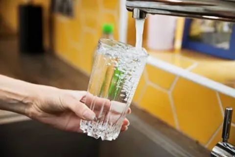 "Hand filling a glass with tap water from a kitchen faucet, symbolizing why untreated tap water in Punta Cana is unsafe for tourists due to contamination risks and unreliable infrastructure."
