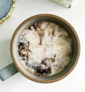 A cup of black coffee on a saucer with a spoonful of powdered Stevia being added, symbolizing the use of Stevia to sweeten coffee during a fast without affecting fat burning or blood sugar levels.