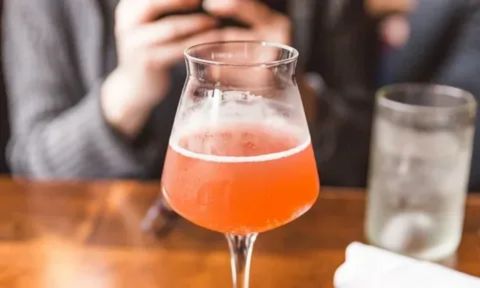 A glass bottle of kombucha next to a bed or on a nightstand, symbolizing a nighttime drink that may cause sleep disruption due to caffeine, carbonation, or probiotic-stimulated digestion.