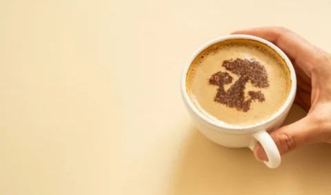 "Hand holding a cup of mushroom coffee with cocoa powder art on top, representing mushroom coffee blends made with reishi, lion’s mane, chaga, and cordyceps."