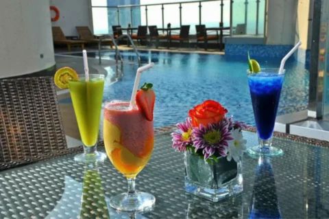 “Colorful drinks on a table beside a pool at a modern venue in Abu Dhabi, representing legal alcohol consumption in approved public locations.”