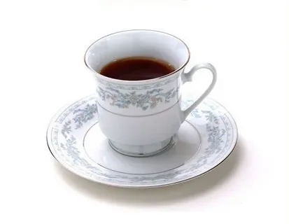 A vintage porcelain teacup filled with dark brewed tea on a matching saucer, representing aged teas like Pu-erh and traditional ancient-tree teas.
