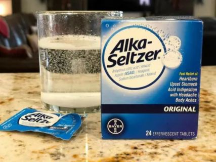 Alka Seltzer box and glass on table representing heartburn relief options for pregnant women and safety concerns during pregnancy.